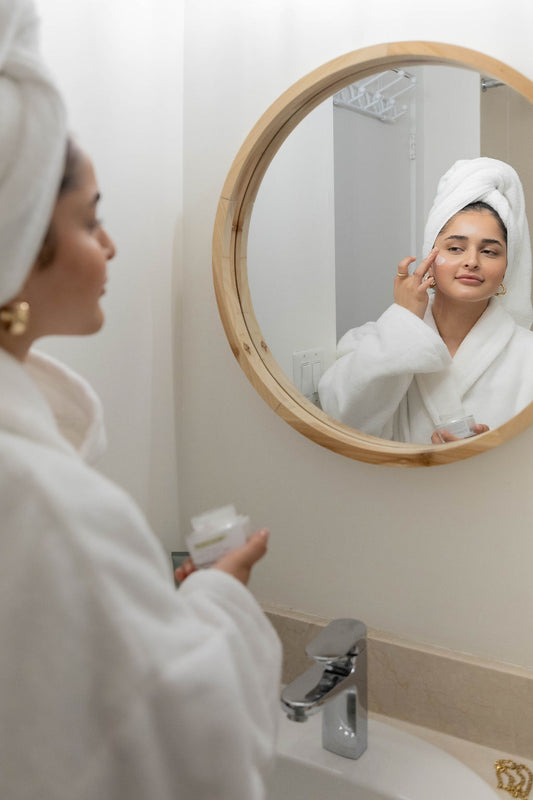 Girl applying a cleanser to wash her face. She is wearing a towel on her head 